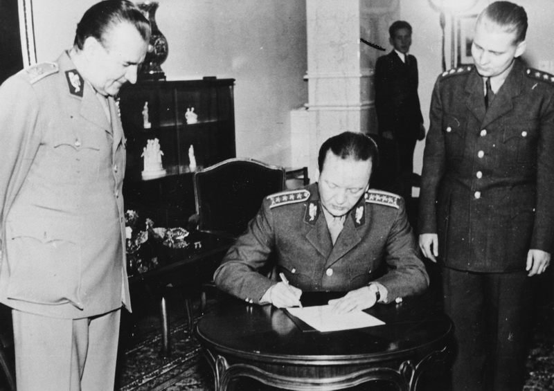 Alexej Čepička při podpisu vojenské přísahy, K. Gottwald stojí po jeho pravé ruce